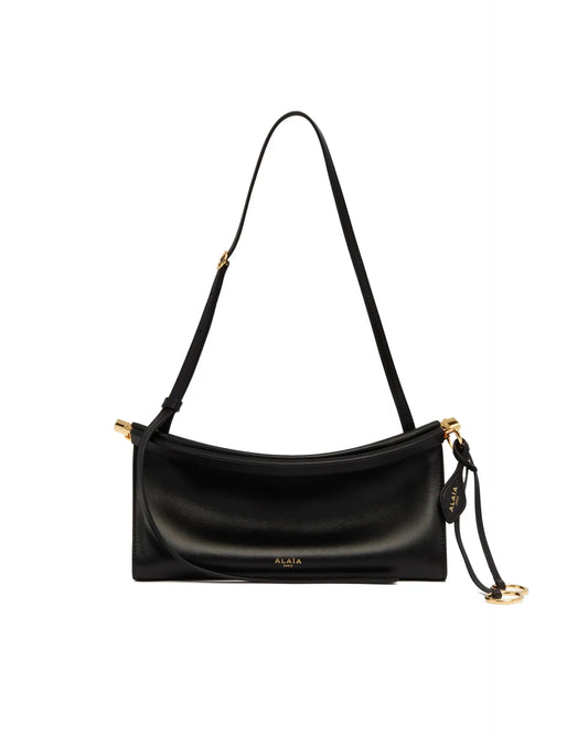 Borsa Le Click East West Piccola In Pelle Nera di Alaia. Pelle nera, forma curva, sistema di apertura a cerniera con rivestimento in pelle, piega sul fondo. Lacci decorativi con anelli metallici, hardware color oro, tracolla regolabile tono su tono. Fodera in pelle. Dimensione (cm): 25X12X8