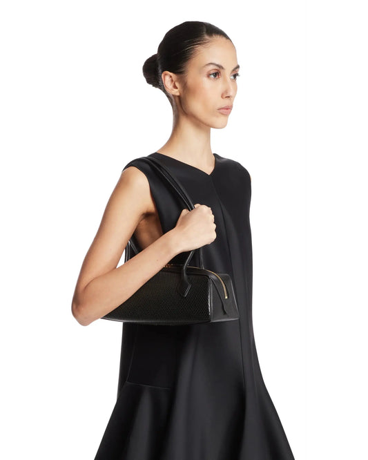 Borsa Le Teckel Media Traforata Nera di Alaia. Realizzata in pelle traforata nera con motivo a rete, forma allungata e manici tubolari in pelle tono su tono con due laccetti decorativi. Chiusura con doppia zip, specchietto removibile nella tasca interna. Dettaglio logo, hardware color oro. Dimensione (cm): 32X10X10